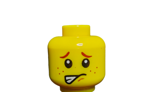 The LEGO 6121896 Minifigure Head UB1489 presents a dual-faced design with one side showing a worried expression with wide eyes, raised eyebrows, freckles, and a tongue sticking out. This head offers endless storytelling possibilities on a plain white background.