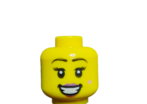 Close-up of a yellow LEGO Minifigure Head (UB1490) featuring cartoonish eyes, arched eyebrows, a wide grin with pink lipstick, and a small pink heart on the cheek adds charm against a white background.