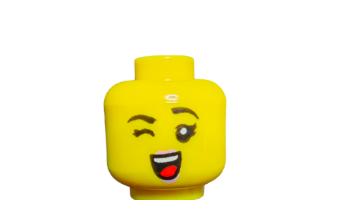 The LEGO 6334588 Minifigure Head features a dual sided female design with black eyebrows, pink lips, and a playful expression: one eye winking and a wide smile showing teeth. Its on a plain white background.
