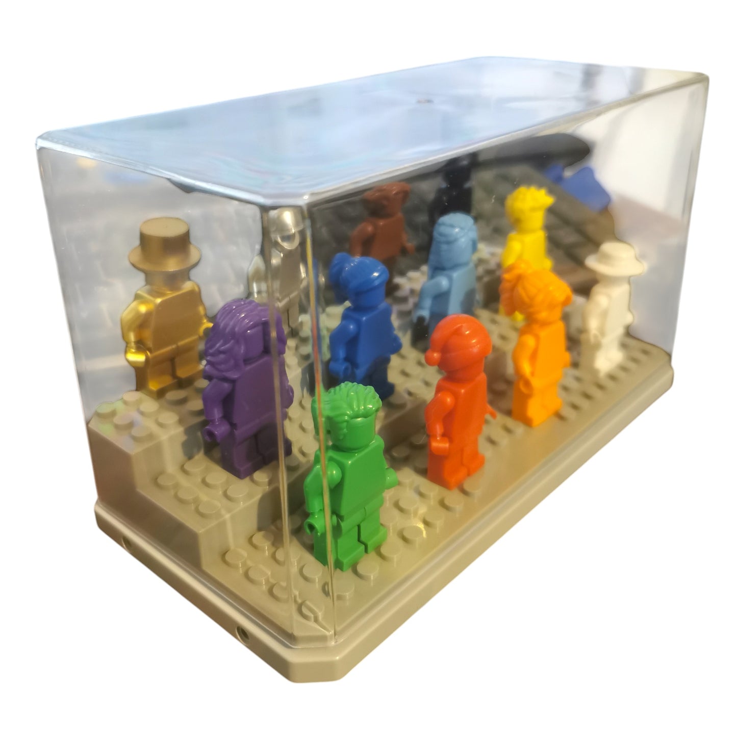 A display case for 12 Vibrant Colour Minifigures features each figure in unique hues, like metallic gold, purple, blue, red, orange, yellow, green, and white. The figures are on a beige base and protected by a transparent lid.