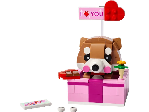 The LEGO® Love Gift Box (40679) features a Shiba Inu dog in a pink box with a red heart saying I ♥ YOU, alongside a yellow flower, and a red heart-shaped gift box. A LOVE white tile and two white dots make it perfect for Valentines Day gifts.