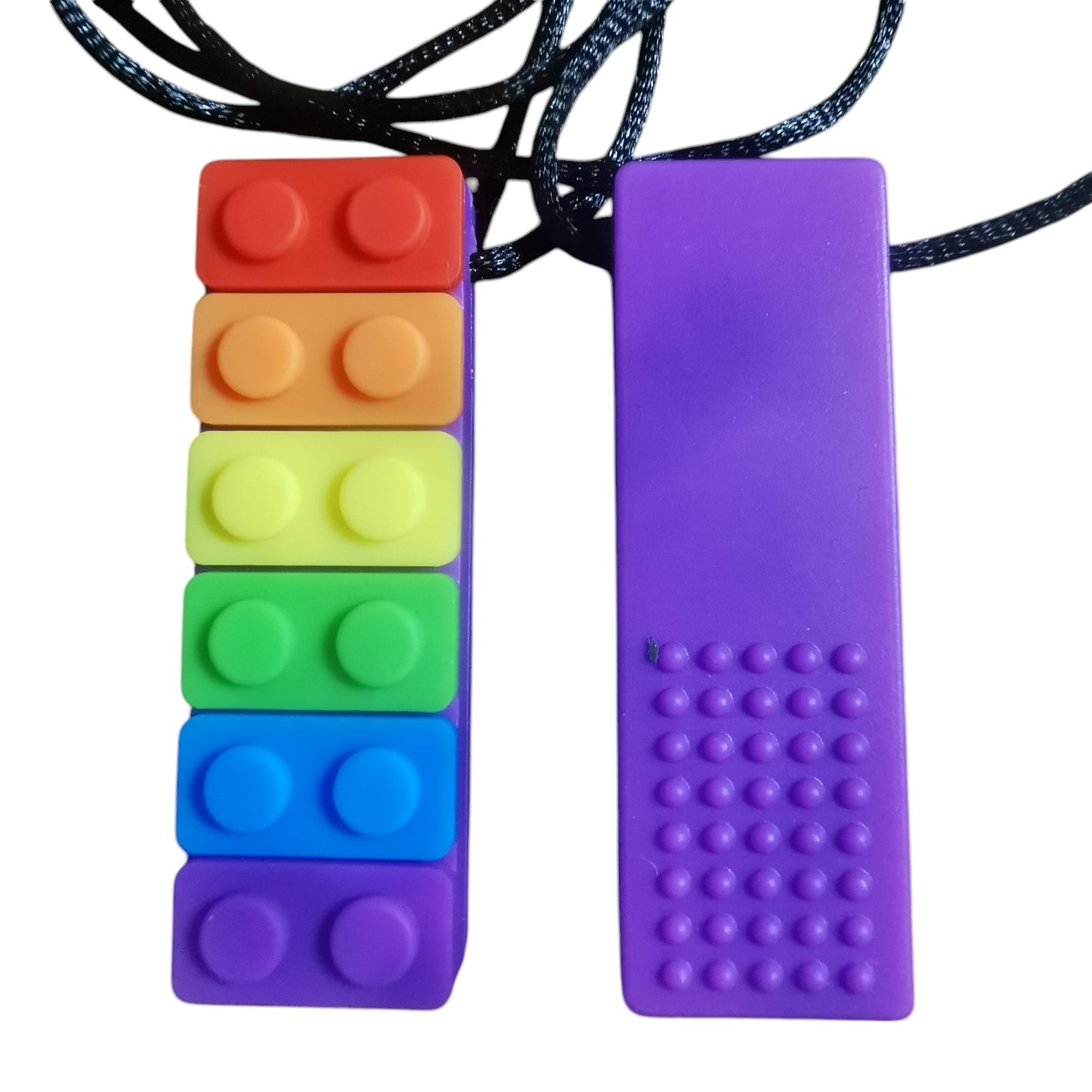 The Rainbow Chew Toys set includes a rainbow brick-shaped necklace and a purple textured dot version, both on black cords. These sensory chew necklaces are ideal for individuals with ADHD or anxiety and provide a calming oral sensory experience.