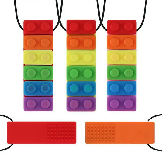 Three vertical stacks of vibrant Sensory Chew Necklace Rainbow Chew Toys for children with ADHD and anxiety dangle above a textured red and orange surface, featuring red, orange, yellow, green, blue, and purple silicone blocks with black cords.