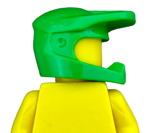 A yellow LEGO minifigure wears a LEGO 6334181 GREEN MOTOBIKE OFFROAD HELMET - UB1382 with a visor and mouthguard, facing right against a plain white background.