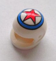 A small round white object with an open mouth-like feature resembles the charm of minifigures. The top has a circular logo featuring a red star inside a blue ring on white. It rests on a plain, light surface. This is part of Motorcycle Helmets for Minifigures, available in various colors and styles.