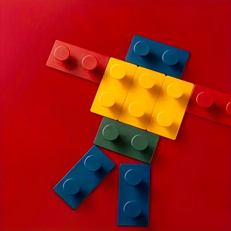 The 4-Pack Creative Building Block Wall Hooks, made from durable ABS resin, are creatively arranged in red, yellow, blue, and green hues to form the head, body, arms, and legs of a figure or robot on a bright red background.