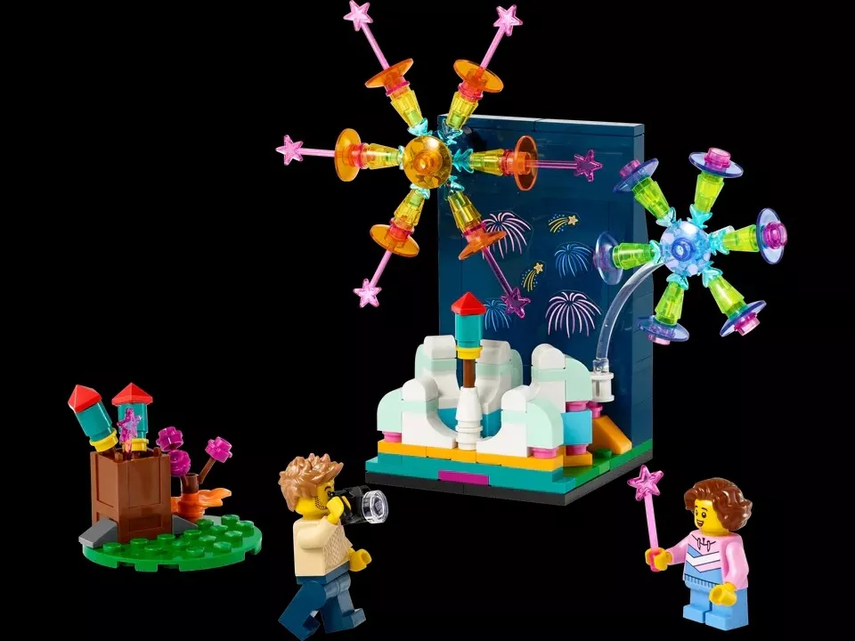 LEGO figures with fireworks display set; includes a boy with a megaphone, a girl with a wand, a cart of rockets, and a colorful background with large fireworks.