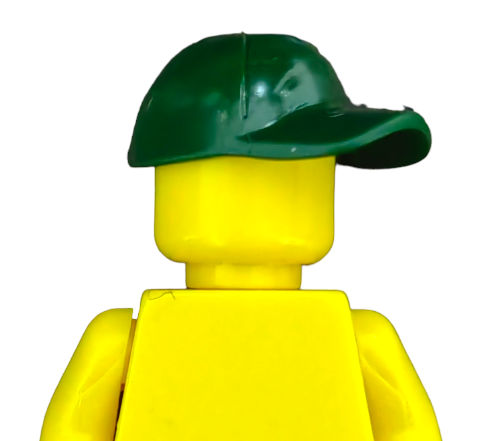 The yellow toy building block figure from PRODUCT HATS AND HOODIES features a smooth head, dark green sideways cap, and a simple design against a plain white background.