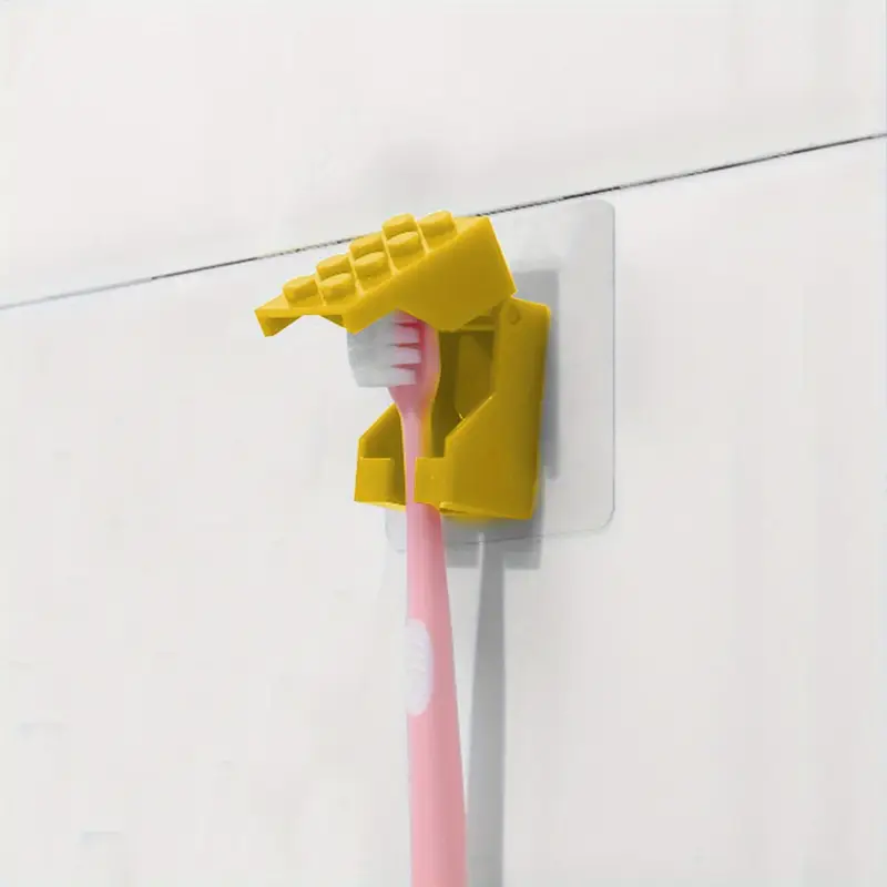 A pink toothbrush is placed in a Kids Childrens Toothbrush Holder, designed in a brick blocks style and wall-mounted, on a pristine white tiled wall.